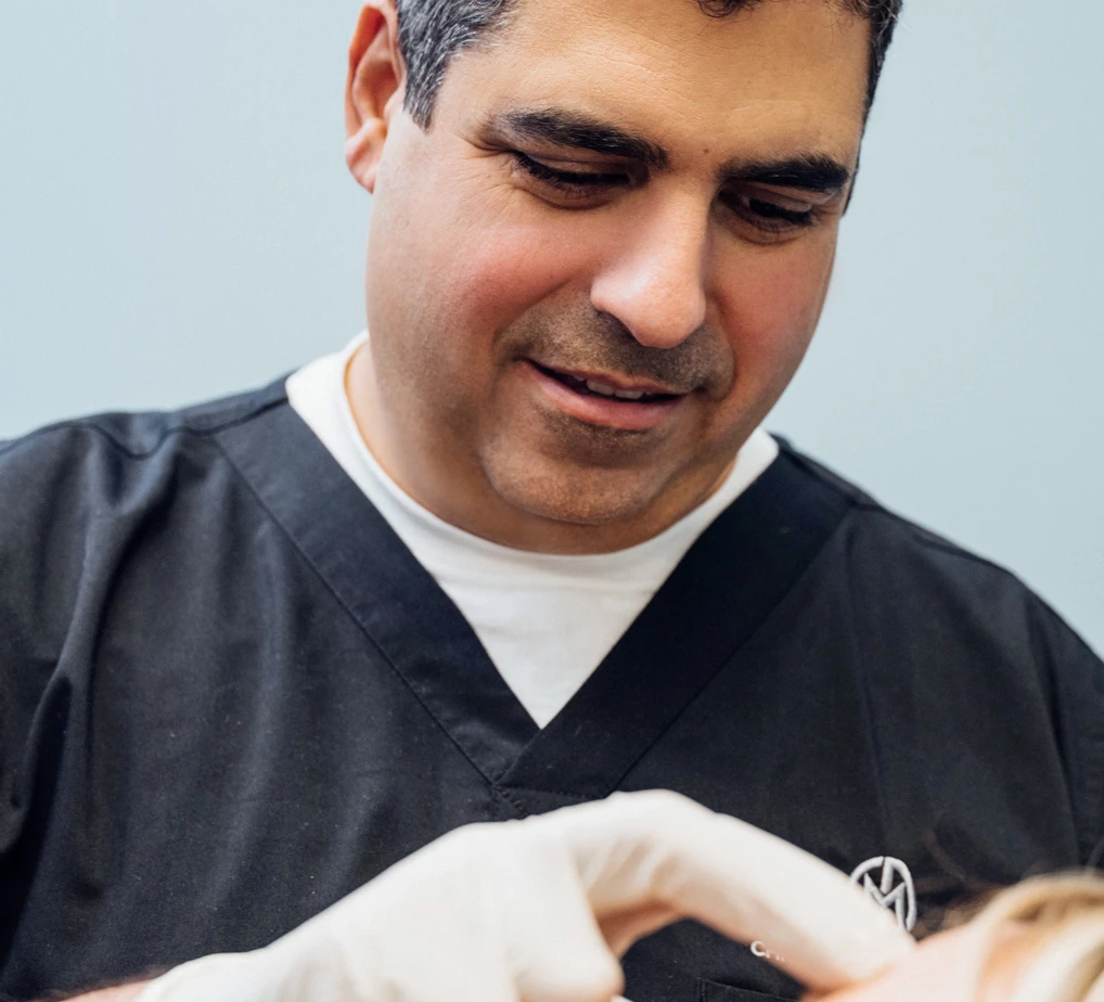 Dr. Christopher Manios applying dermal filler injections on a patient